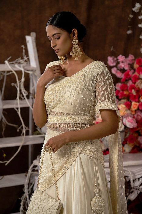 A model showcasing Ivory Lehenga Set With Handbag by Farha Syed from Farha Syed's collection