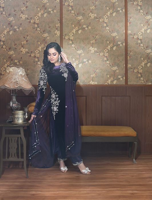 A model showcasing Zia Purple Velvet Suit Set by Ayushi Agarwal from Ayushi Agarwal's collection A model showcasing Zia Purple Velvet Suit Set by Ayushi Agarwal from Ayushi Agarwal's collection