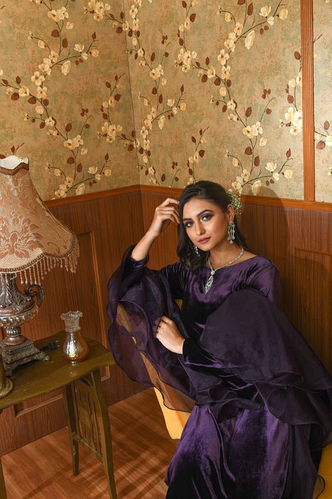 A model showcasing Purple Liora Velvet Suit Set by Ayushi Agarwal from Ayushi Agarwal's collection A model showcasing Purple Liora Velvet Suit Set by Ayushi Agarwal from Ayushi Agarwal's collection