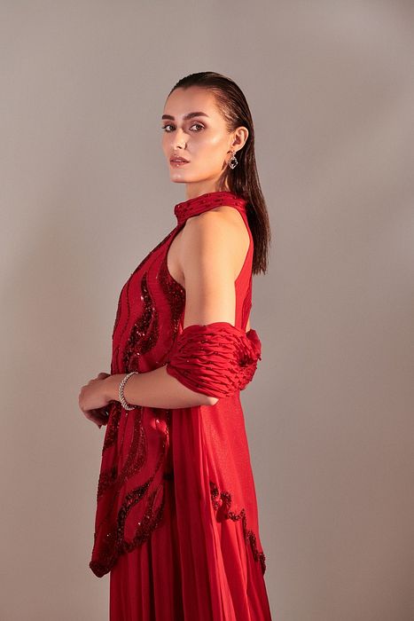 A model showcasing Scarlet Red Cutwork Asymmetric Tunic And Twisted Pleats Dupatta by One Knot One from One Knot One's collection