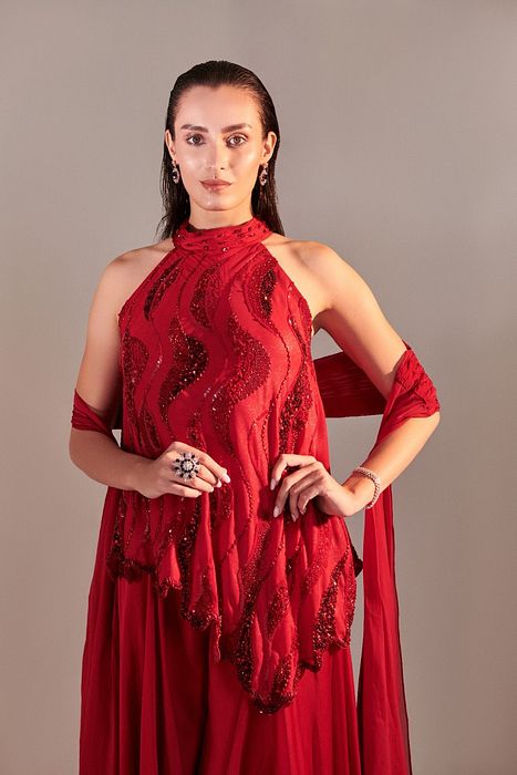 A model showcasing Scarlet Red Cutwork Asymmetric Tunic And Twisted Pleats Dupatta by One Knot One from One Knot One's collection
