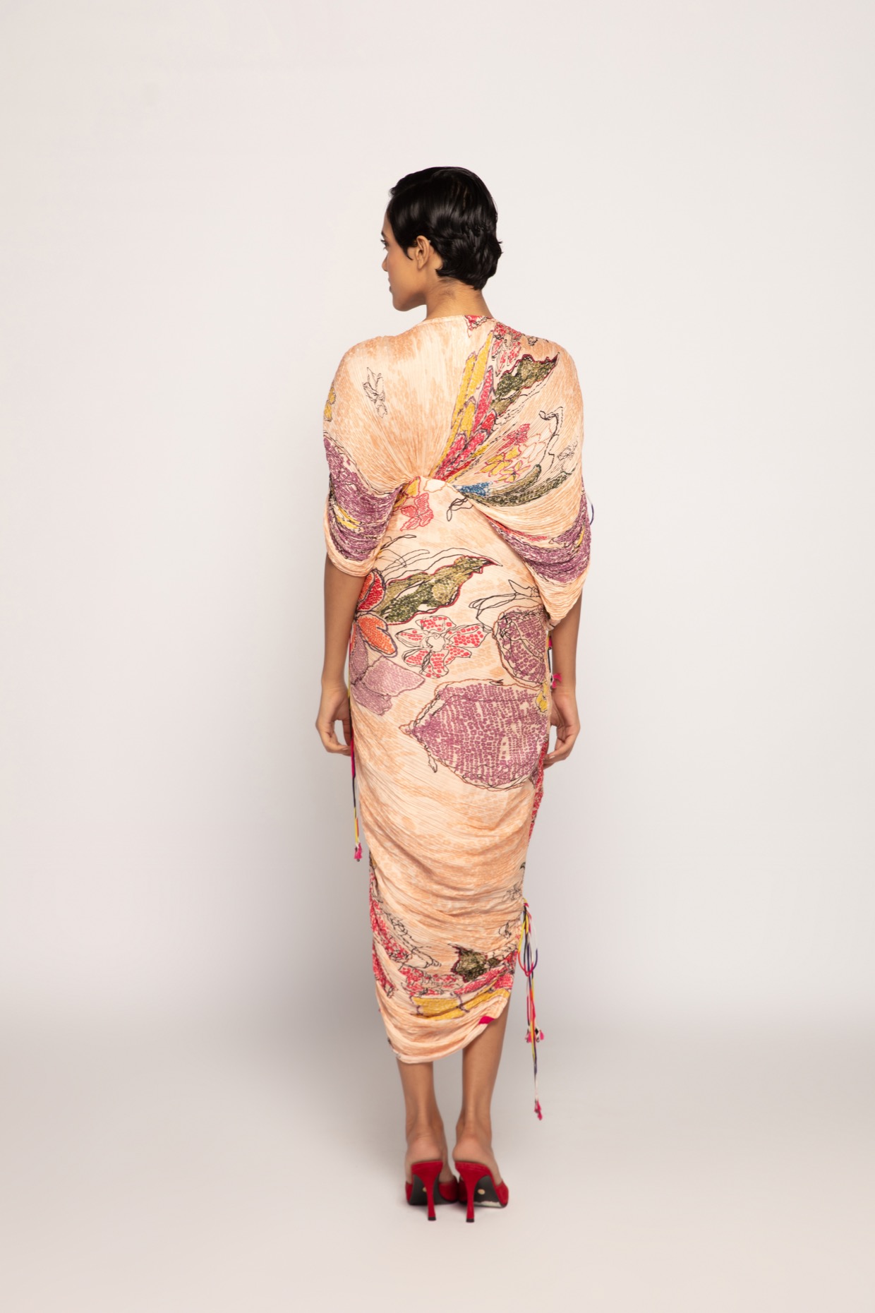 A model showcasing Periwinkle Bandhani Print Peach Pleated Maxi Dress by Saaksha And Kinni from Saaksha And Kinni's collection