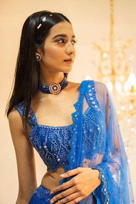 A model showcasing Blue Tiered Mirror Work Lehenga Set by Foram Patel from Foram Patel's collection