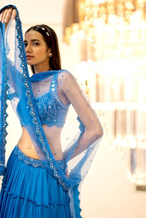 A model showcasing Blue Tiered Mirror Work Lehenga Set by Foram Patel from Foram Patel's collection