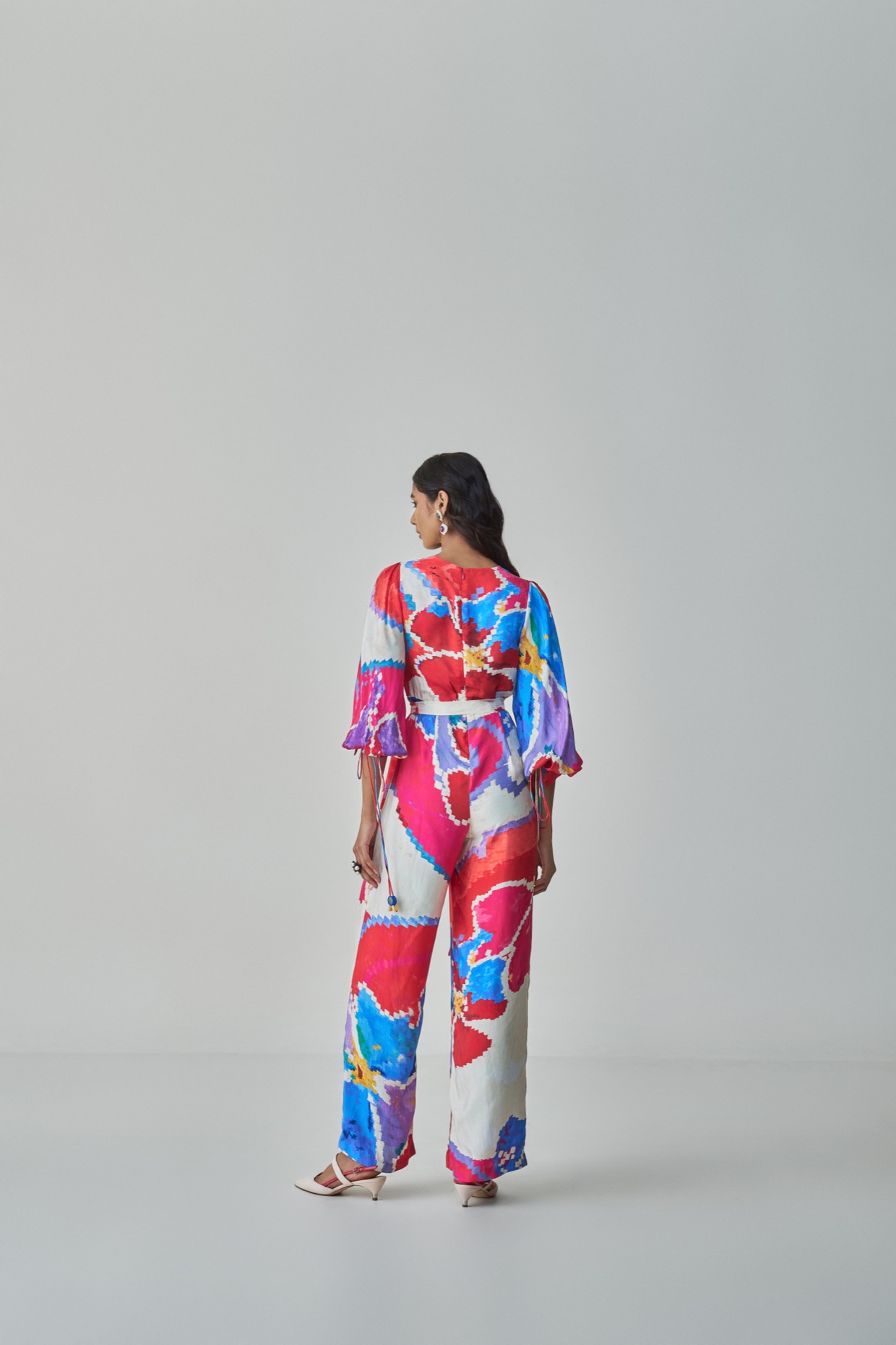 A model showcasing Jenny Jumpsuit Pink Red Overlap Jumpsuit by Saaksha And Kinni from Saaksha And Kinni's collection