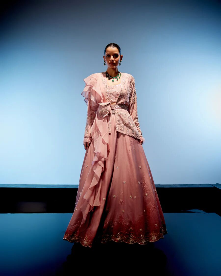 A model showcasing Peach Pink Rose Lehenga by Miku Kumar from Miku Kumar's collection