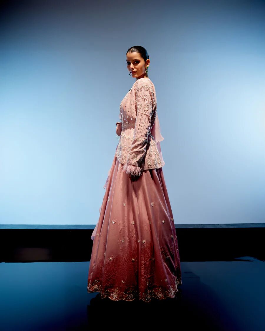 A model showcasing Peach Pink Rose Lehenga by Miku Kumar from Miku Kumar's collection
