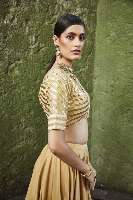 A model showcasing Gold Silk Lehenga by Ranian from Ranian's collection A model showcasing Gold Silk Lehenga by Ranian from Ranian's collection