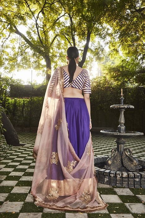 A model showcasing Purple Silk Lehenga by Ranian from Ranian's collection A model showcasing Purple Silk Lehenga by Ranian from Ranian's collection