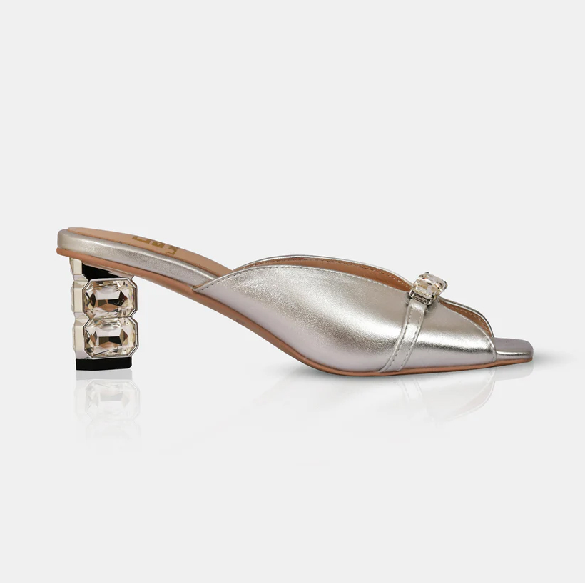 A model showcasing Silver Metallic Leather Sandals With Crystal Heel by Elleganti from Elleganti's collection A model showcasing Silver Metallic Leather Sandals With Crystal Heel by Elleganti from Elleganti's collection