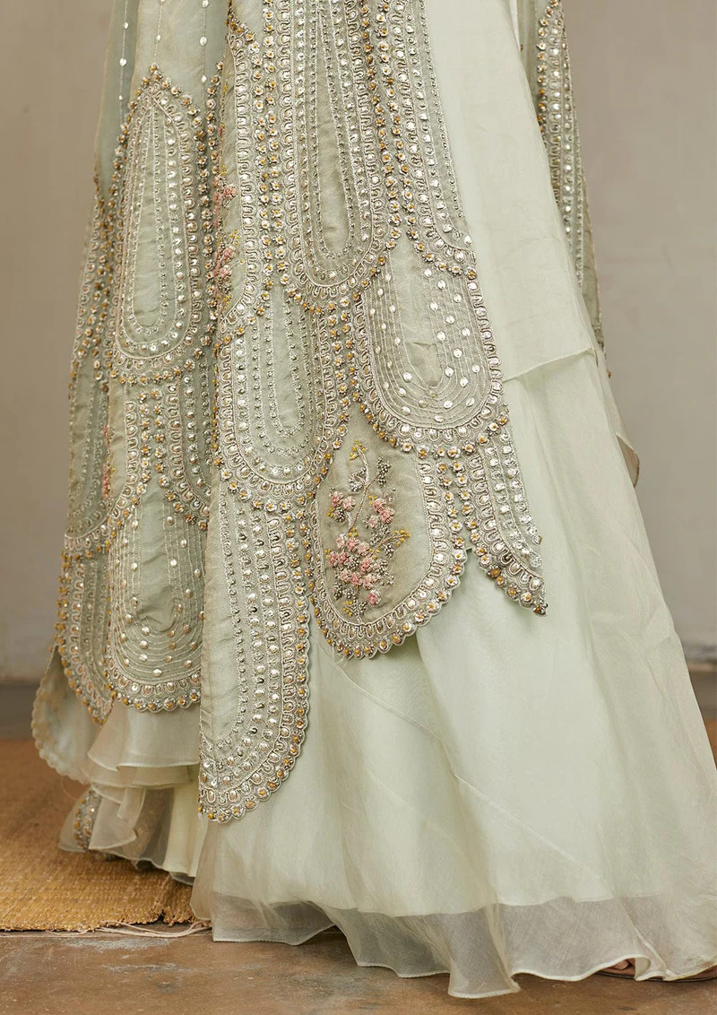 A model showcasing Ivory Optical Embroidered Jacket Lehenga Set by Ossa from Ossa's collection A model showcasing Ivory Optical Embroidered Jacket Lehenga Set by Ossa from Ossa's collection