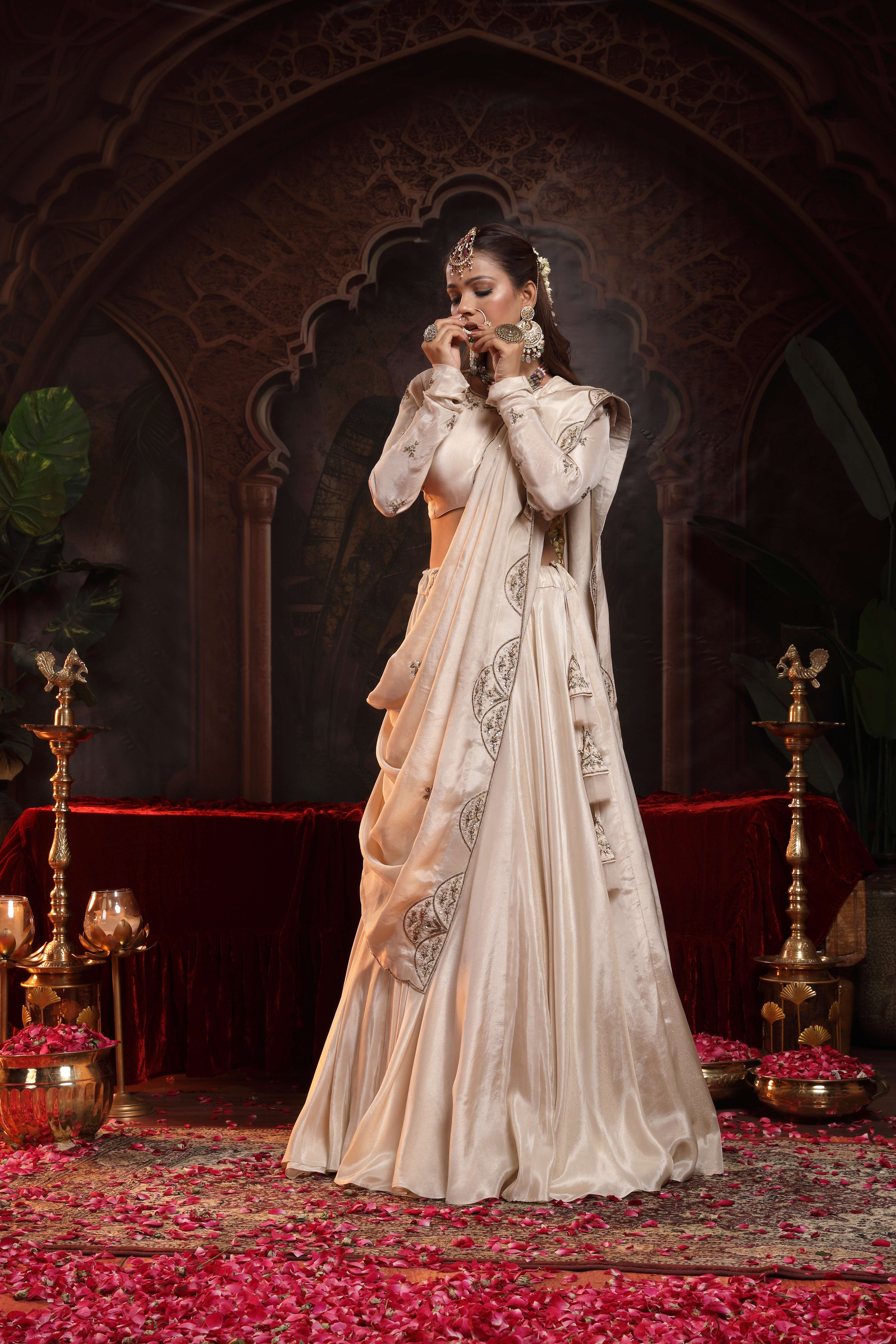 A model showcasing Nihar Ivory Lehenga Set by Miku Kumar from Miku Kumar's collection
