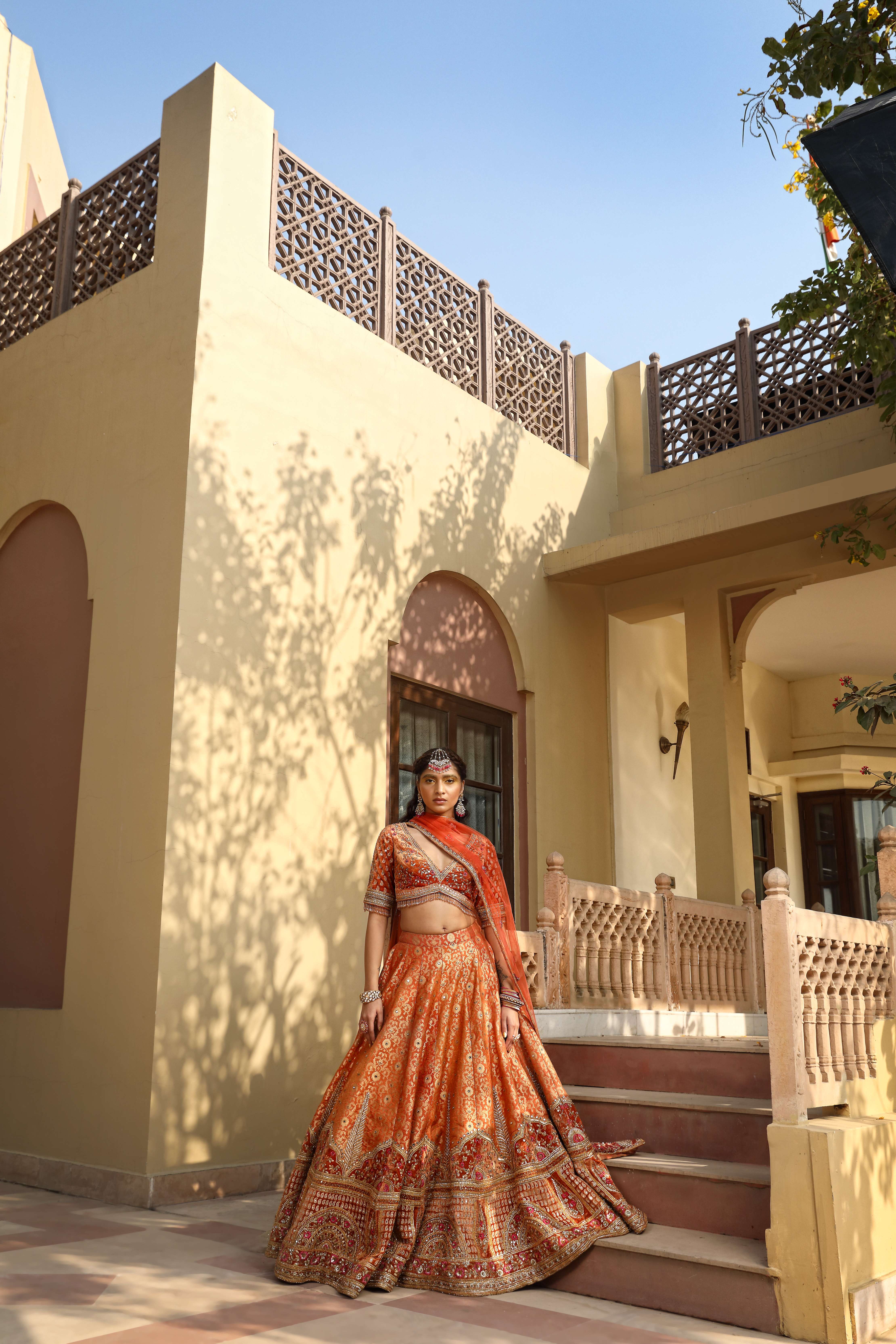 A model showcasing Rust Lehenga Choli Set by Mavish from Mavish's collection