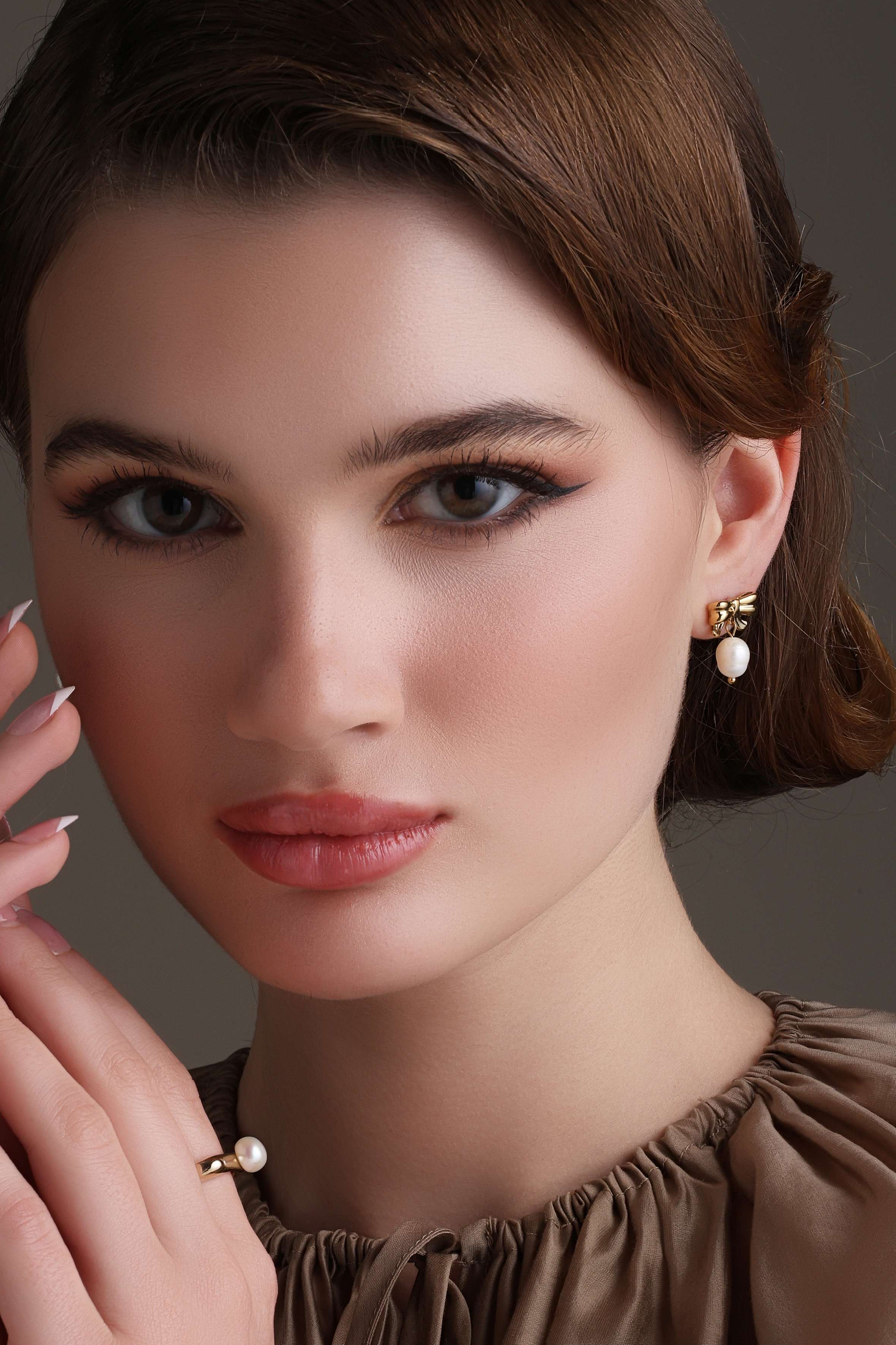 A model showcasing Bow Charm Dang Earrings by Dusala from Dusala's collection A model showcasing Bow Charm Dang Earrings by Dusala from Dusala's collection