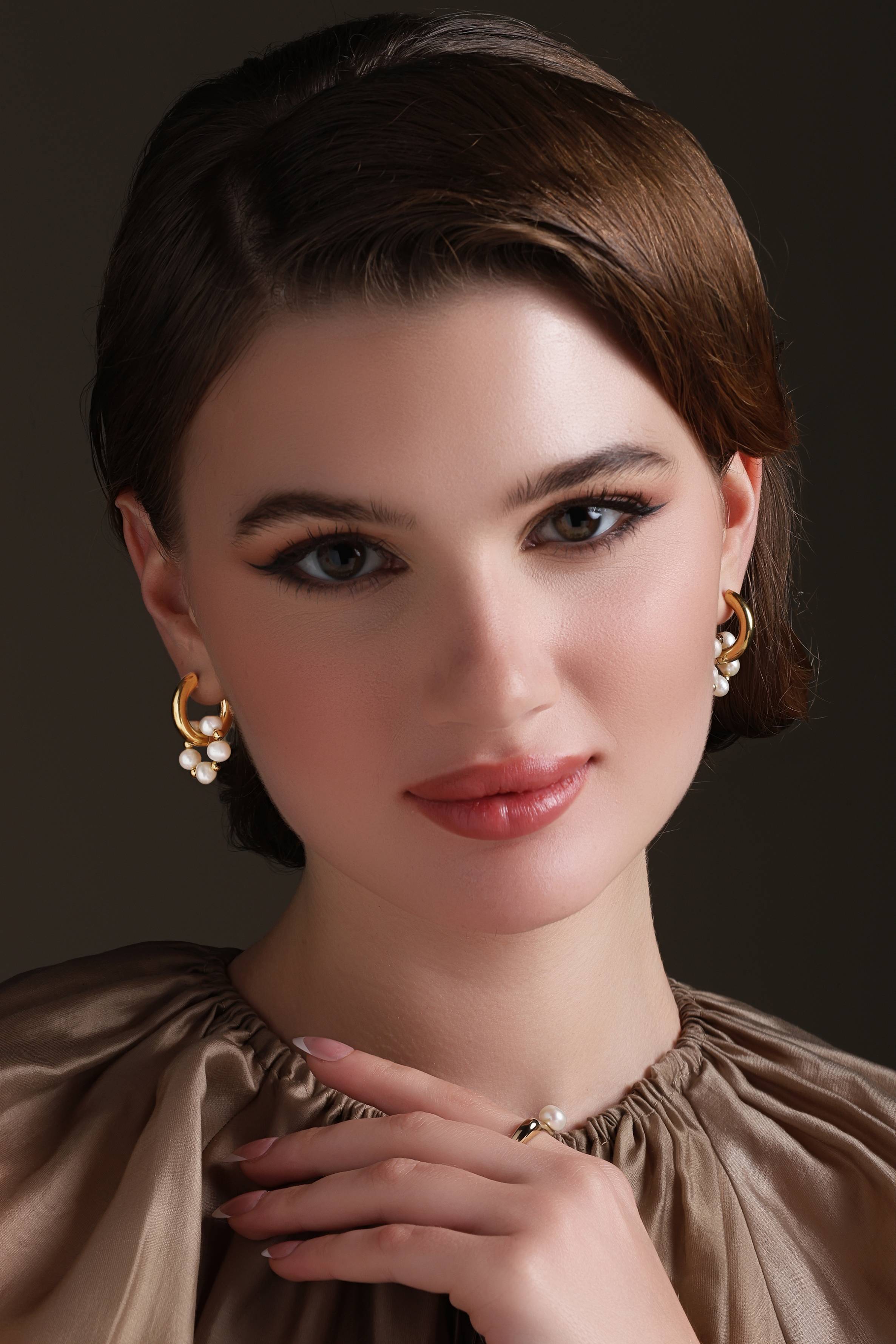 A model showcasing Huggie Trend Earrings by Dusala from Dusala's collection