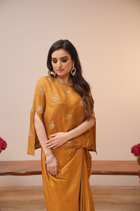 A model showcasing Mustard Cape And Dhoti Set by Myra By Anju Narian from Myra By Anju Narian's collection A model showcasing Mustard Cape And Dhoti Set by Myra By Anju Narian from Myra By Anju Narian's collection