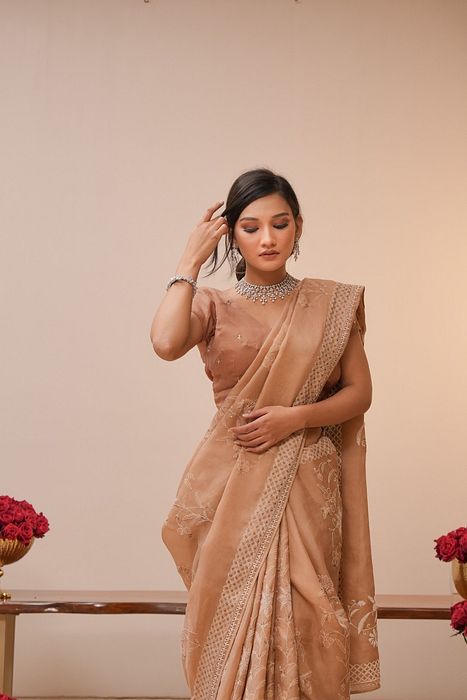 A model showcasing Brown Organza Chikankari Saree by Myra By Anju Narian from Myra By Anju Narian's collection A model showcasing Brown Organza Chikankari Saree by Myra By Anju Narian from Myra By Anju Narian's collection