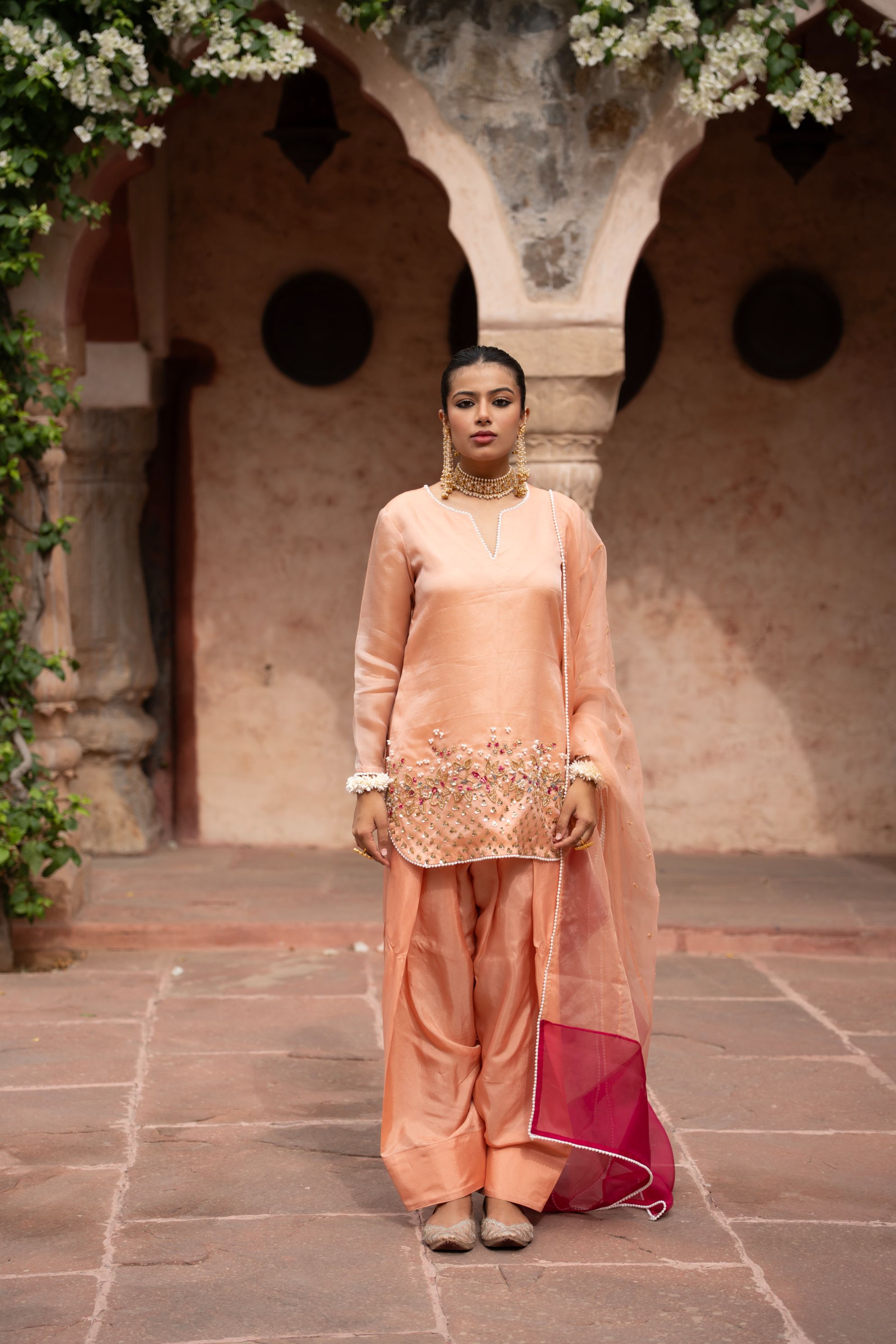 A model showcasing Peach Pink Handembroidered Farshi Set by Nikunj from Nikunj's collection