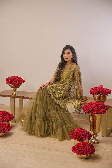 A model showcasing Khaki Tier Skirt With Cape by Myra By Anju Narian from Myra By Anju Narian's collection A model showcasing Khaki Tier Skirt With Cape by Myra By Anju Narian from Myra By Anju Narian's collection