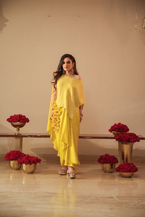 A model showcasing Chikankari Asymmetrical Tunic With Tassels And Dhoti by Myra By Anju Narian from Myra By Anju Narian's collection A model showcasing Chikankari Asymmetrical Tunic With Tassels And Dhoti by Myra By Anju Narian from Myra By Anju Narian's collection