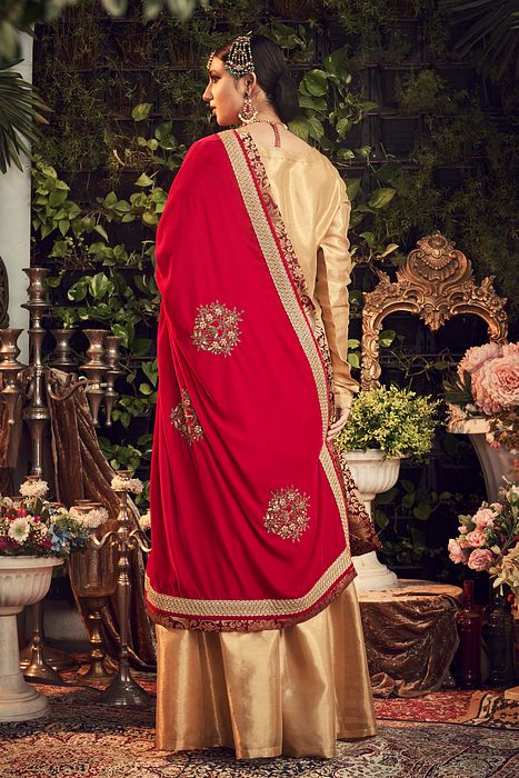 A model showcasing Oxidised Gold Garara Set With Red Velvet Dupatta by Ranian from Ranian's collection A model showcasing Oxidised Gold Garara Set With Red Velvet Dupatta by Ranian from Ranian's collection