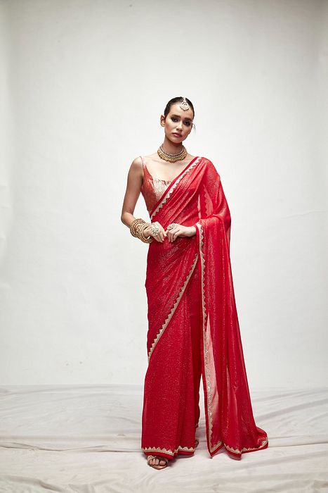 A model showcasing Carmine Red Mettalic Saree Set by Ranian from Ranian's collection A model showcasing Carmine Red Mettalic Saree Set by Ranian from Ranian's collection