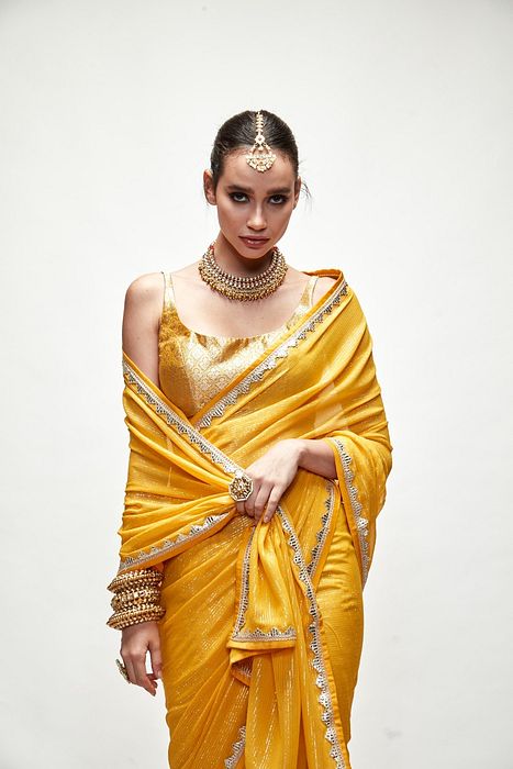 A model showcasing Dandelion Yellow Mettalic Saree Set by Ranian from Ranian's collection A model showcasing Dandelion Yellow Mettalic Saree Set by Ranian from Ranian's collection