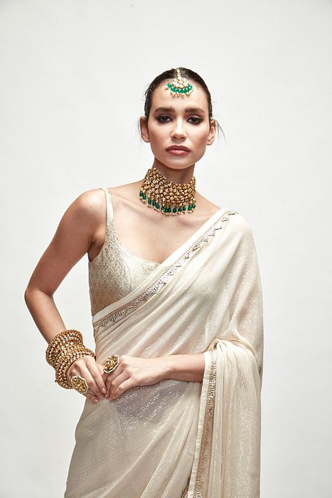 A model showcasing Porcelain Cream Mettalic Saree Set by Ranian from Ranian's collection A model showcasing Porcelain Cream Mettalic Saree Set by Ranian from Ranian's collection