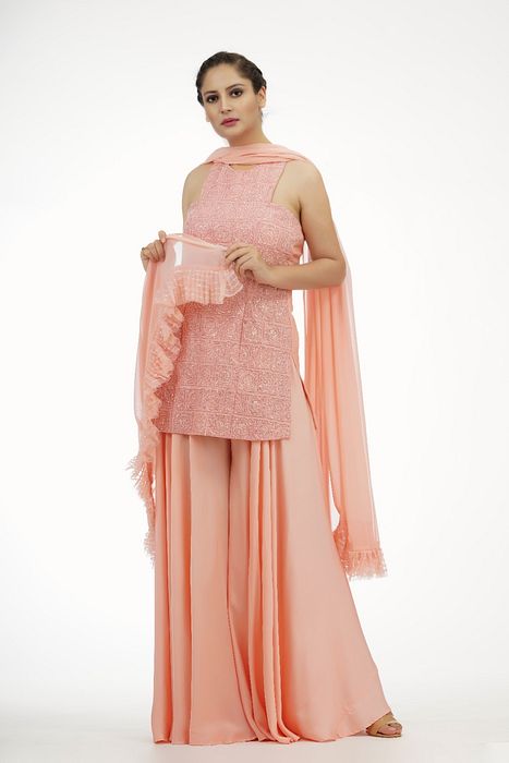 A model showcasing Peach Racer Cut Sharara Suit by Shruti S Label from Shruti S Label's collection
